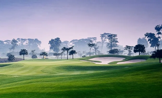 Jakarta Golf Club Rawamangun dengan fairway hijau, bunker pasir, dan suasana pagi berkabut.