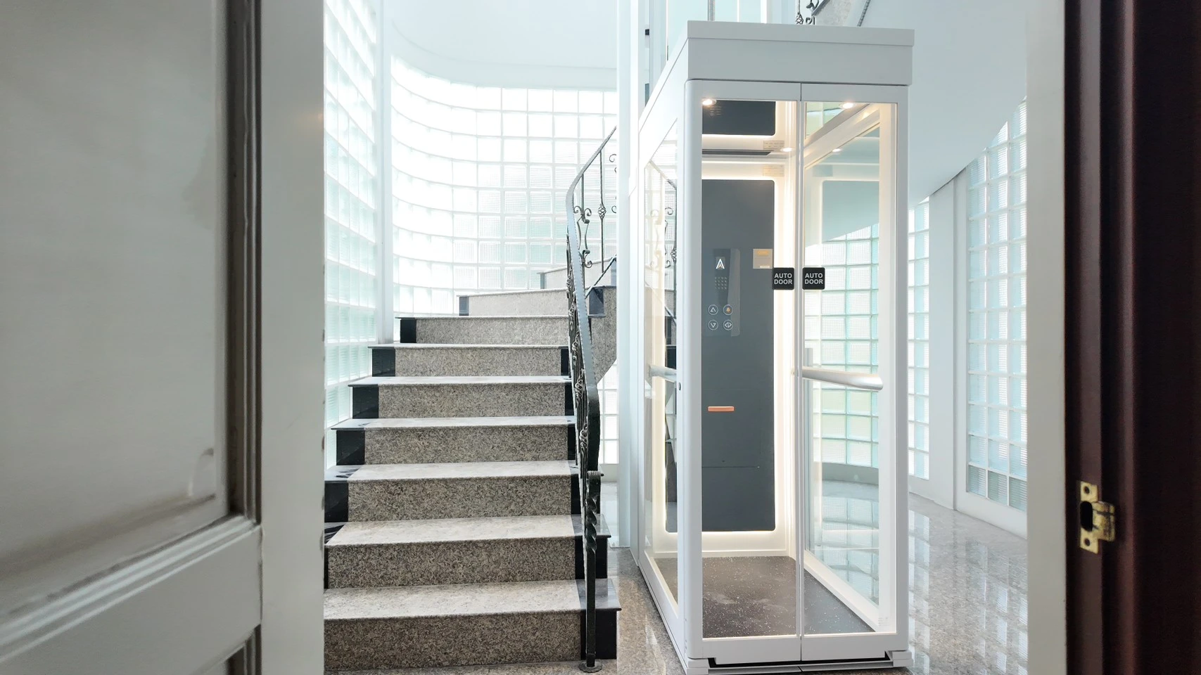 Close-up pintu lift kaca Ascenda yang terbuka, menampilkan panel kontrol, pencahayaan interior, dan akses masuk yang nyaman