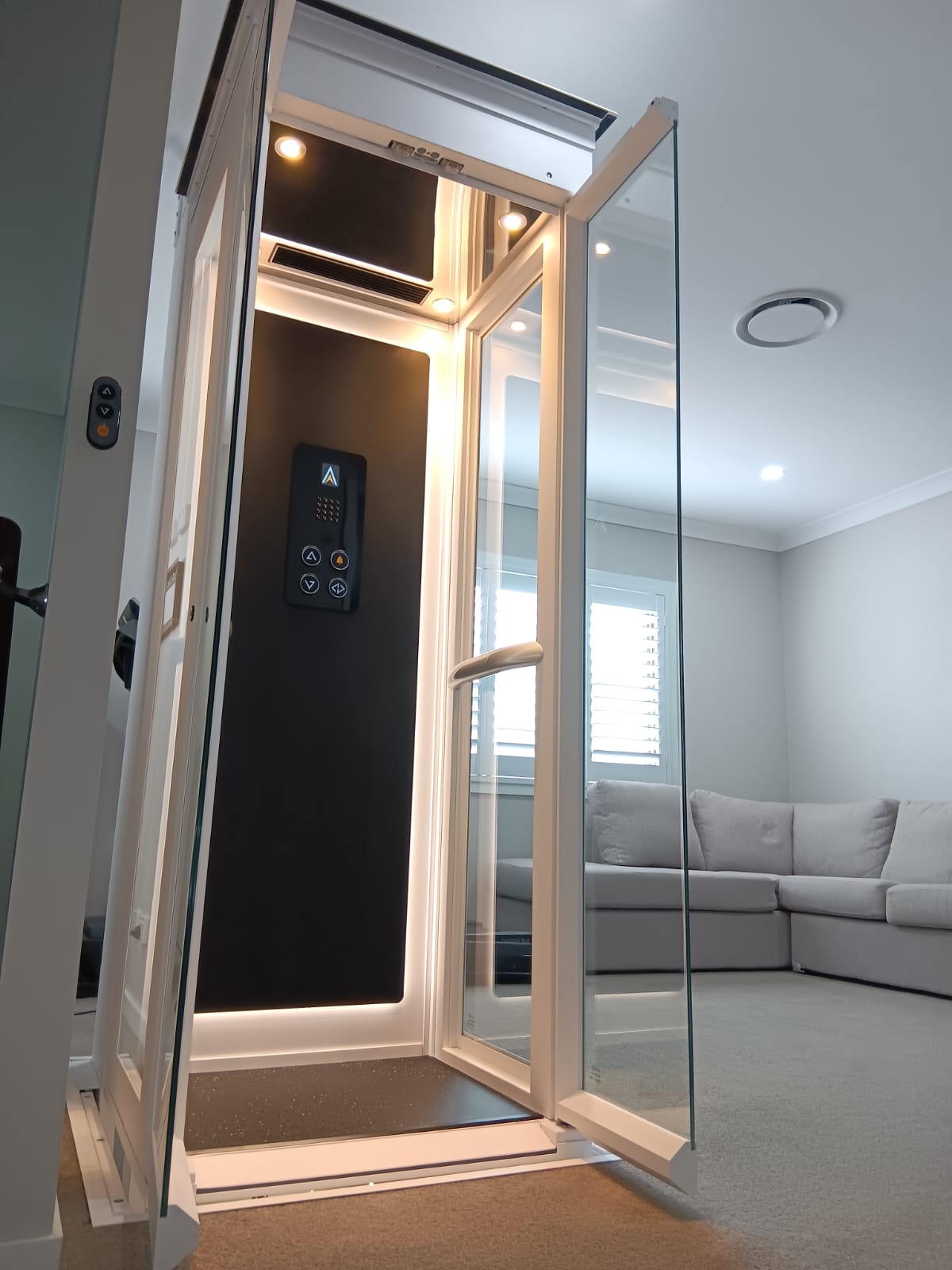 Ascenda Size S dengan pintu kaca terbuka di ruang keluarga, menampilkan lift rumah yang aman dan ringkas untuk lansia di rumah bertingkat.