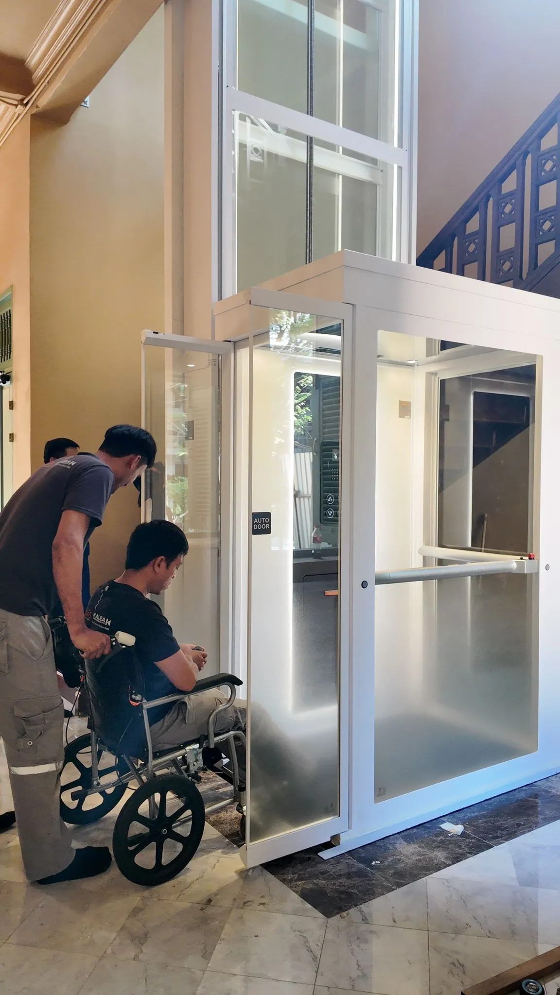 Lift rumah Ascenda dengan pengguna kursi roda masuk ke kabin bersama pendamping