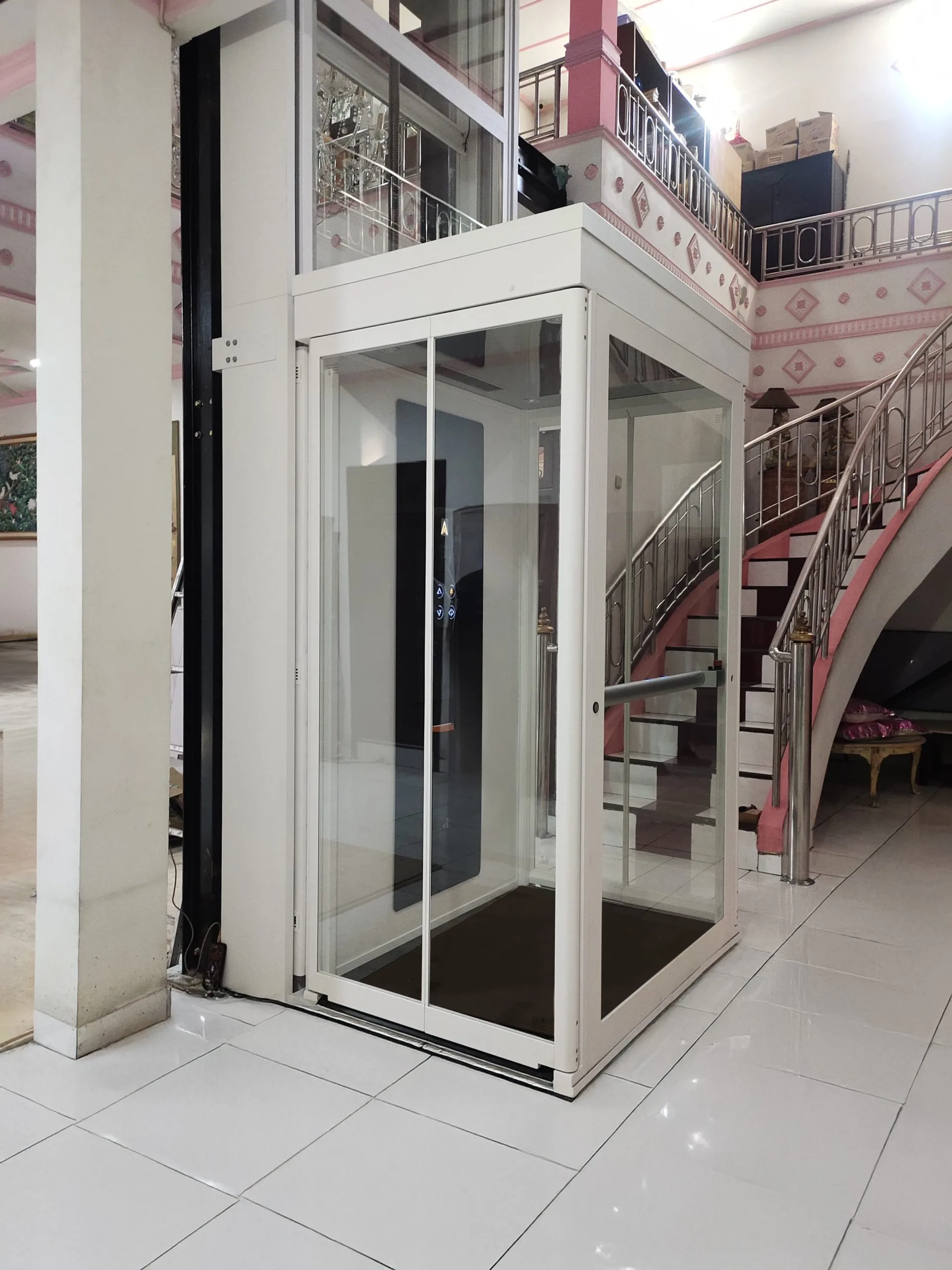 Lift rumah Ascenda putih model pitless terpasang di area tangga rumah tinggal di Surabaya